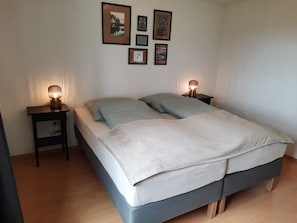 Une chambre à coucher avec un lit, deux tables de chevet et des tableaux accrochés au mur.