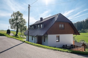 A two-story house with a sloped roof, a small porch, and a visible chimney.