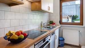 A modern kitchen with a built-in stove, a window with a view, and a fruit bowl on the counter. - Holiday Apartment 'West' with Shared Terrace, Shared Garden and Balcony (Eisenbach (Hochschwarzwald))