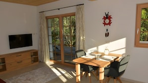 Een eetgedeelte met een houten tafel, stoelen, een televisie, een houten kast en een groot raam met gordijnen.