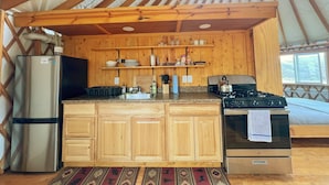 Una cocina compacta con armarios de madera, un refrigerador, una estufa y un lavamanos.