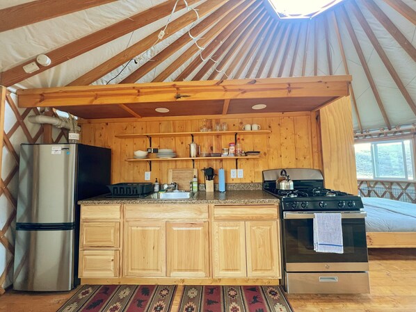 Una cocina compacta con armarios de madera, un refrigerador, una estufa y un lavamanos.