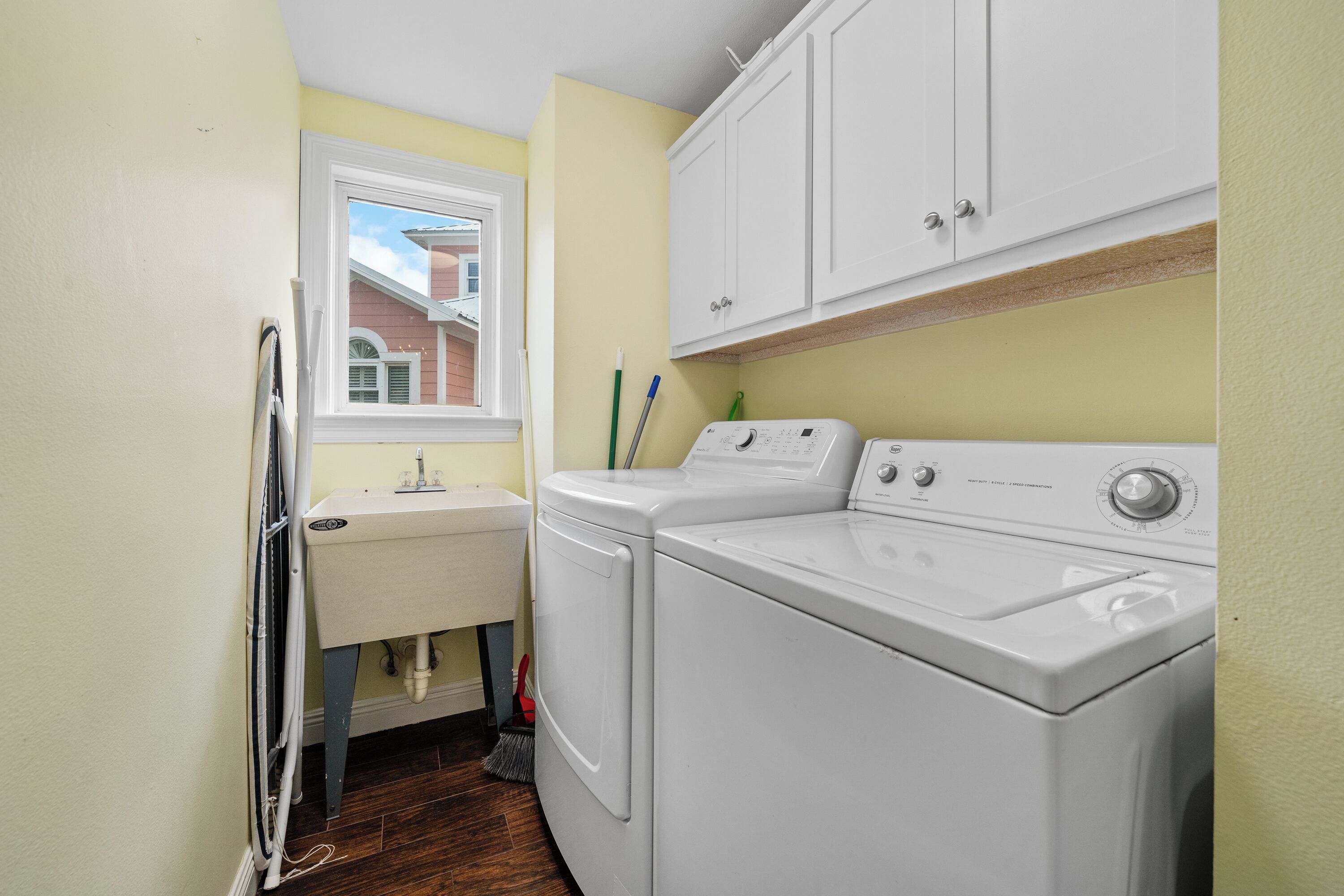 A laundry area with a washing machine, a sink, and cabinets.