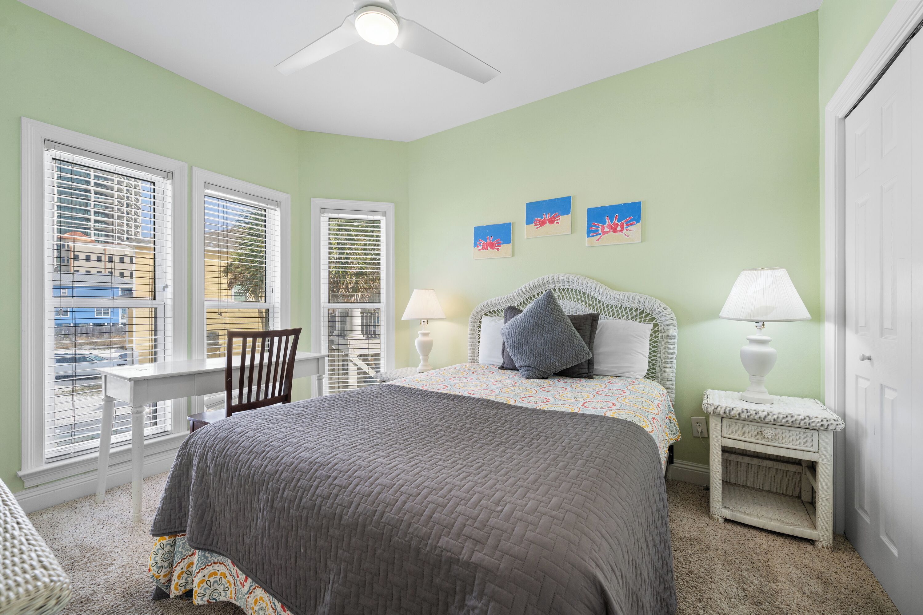 A bedroom with a bed, two bedside tables, a chair, and a window with blinds.
