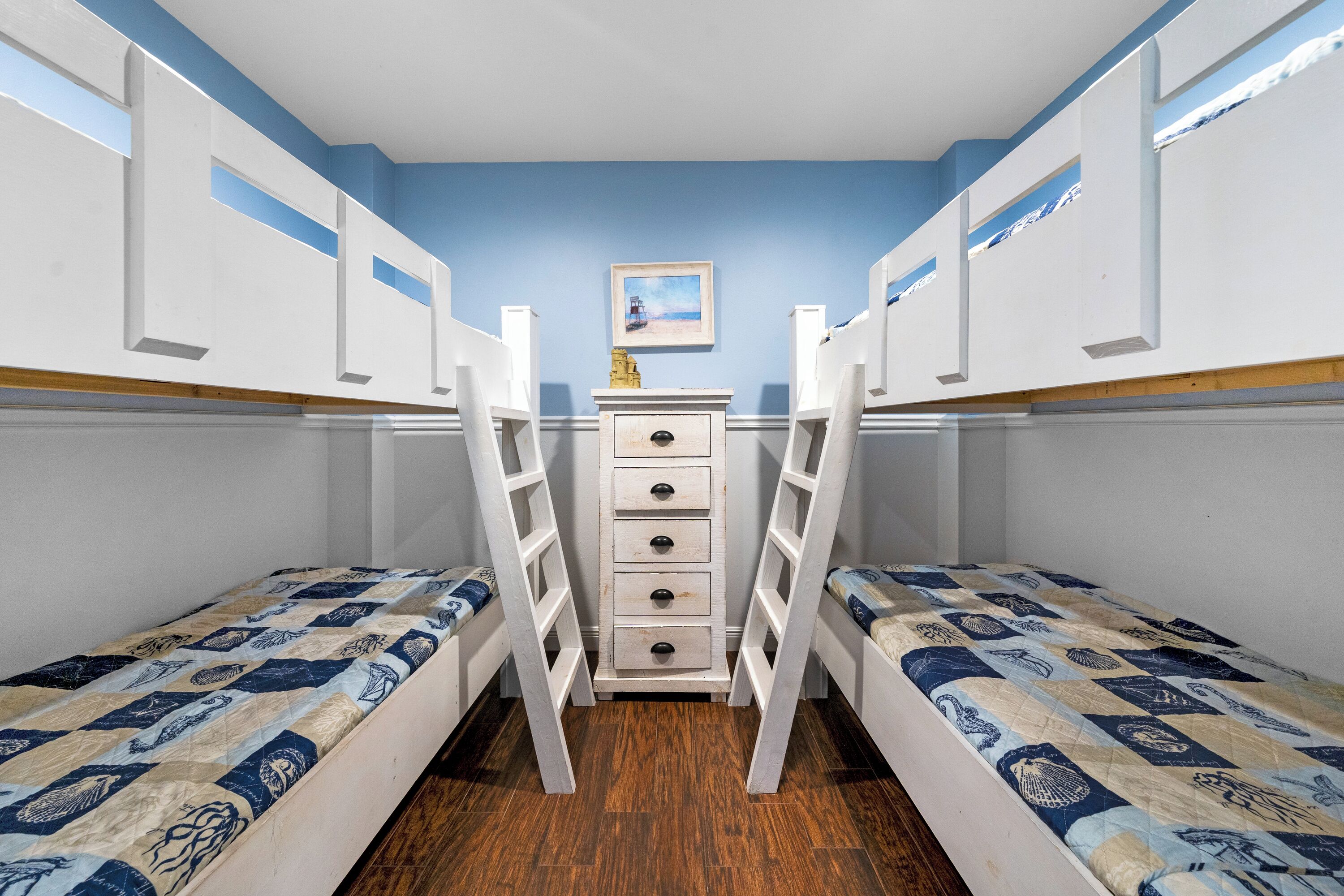 A room with bunk beds, a dresser, and a painting on the wall.