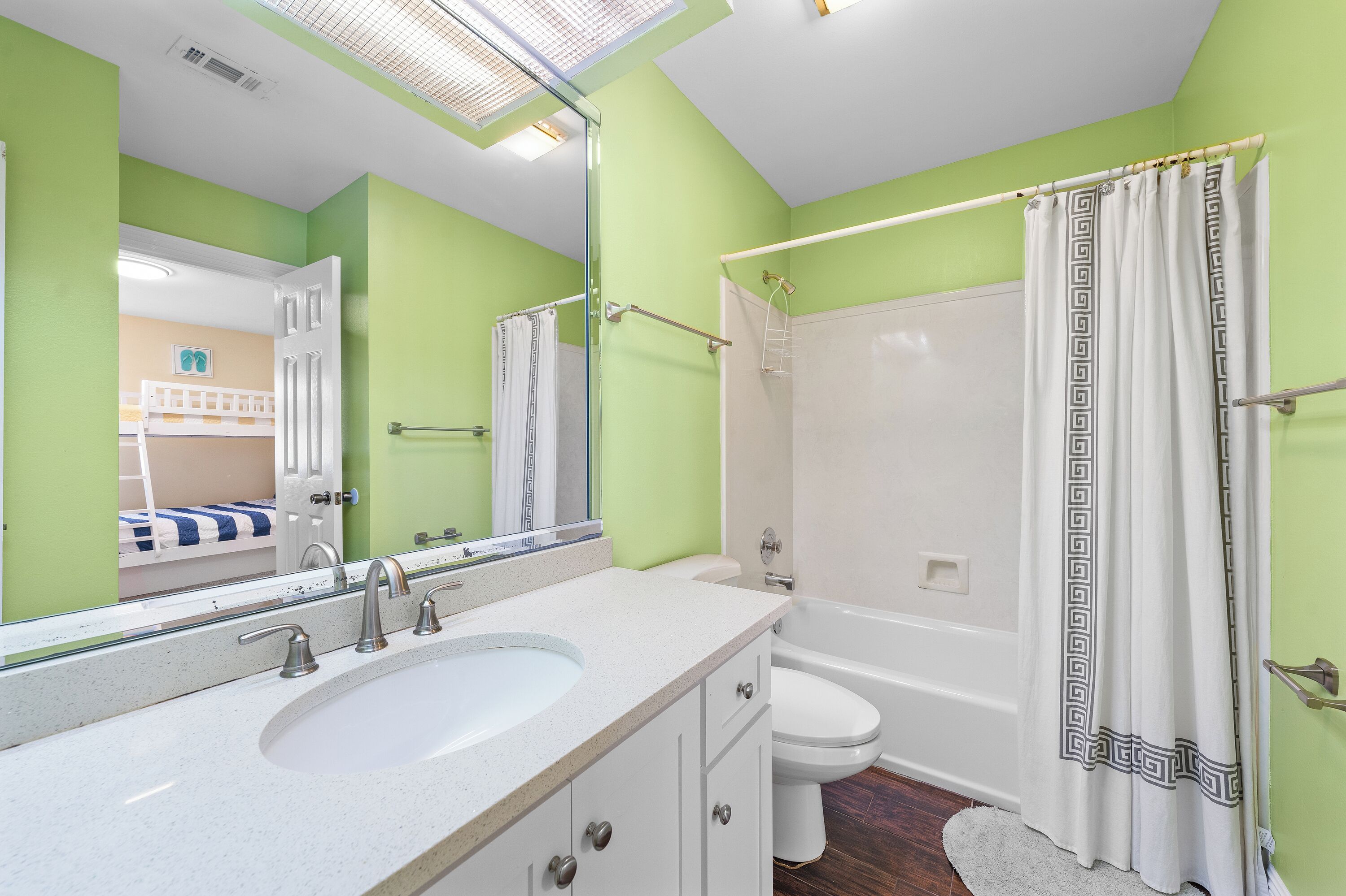 Une salle de bain avec un grand miroir, un lavabo, des toilettes et une douche.