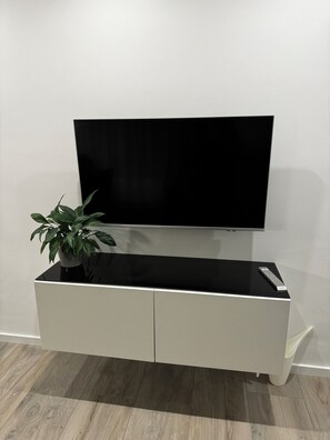 Entertainment unit features a flat-screen TV and a sleek cabinet with a glossy top surface.