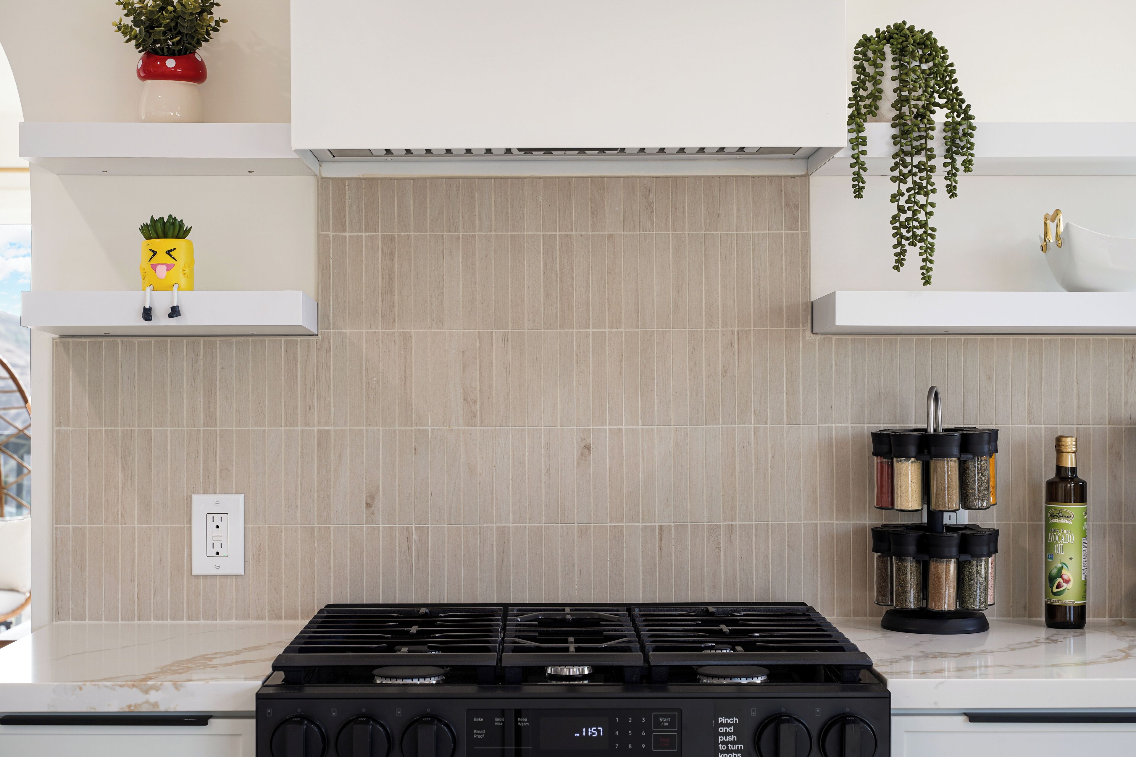 A kitchen with a gas stove, a spice rack, and a bottle of oil.