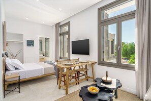 Ein modernes Schlafzimmer mit Bett, Esstisch, Stühlen, einem Fernseher und einem Fenster mit Blick.