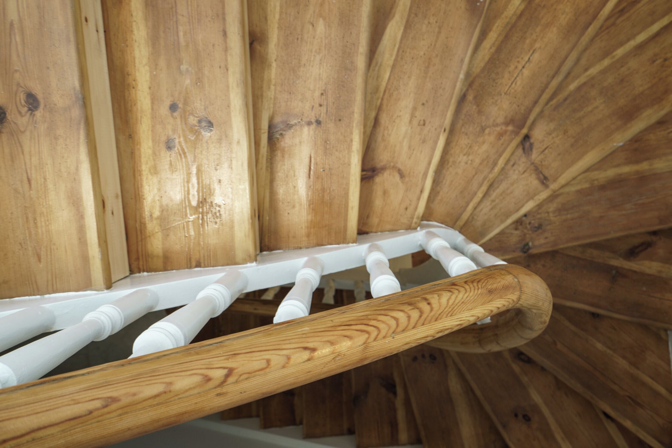 Un escalier en bois avec des balustrades blanches et une main courante en bois.