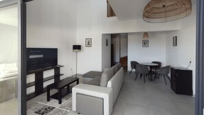 A modern living room with a sofa, a coffee table, a TV, and a dining area with chairs and a table. - T4 duplex and rooftop in the heart of Saint-Pierre, this new luxury residence be (Saint-Pierre)