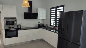 A modern kitchen with white cabinets, a black refrigerator, a microwave, and a toaster. - T4 duplex and rooftop in the heart of Saint-Pierre, this new luxury residence be (Saint-Pierre)