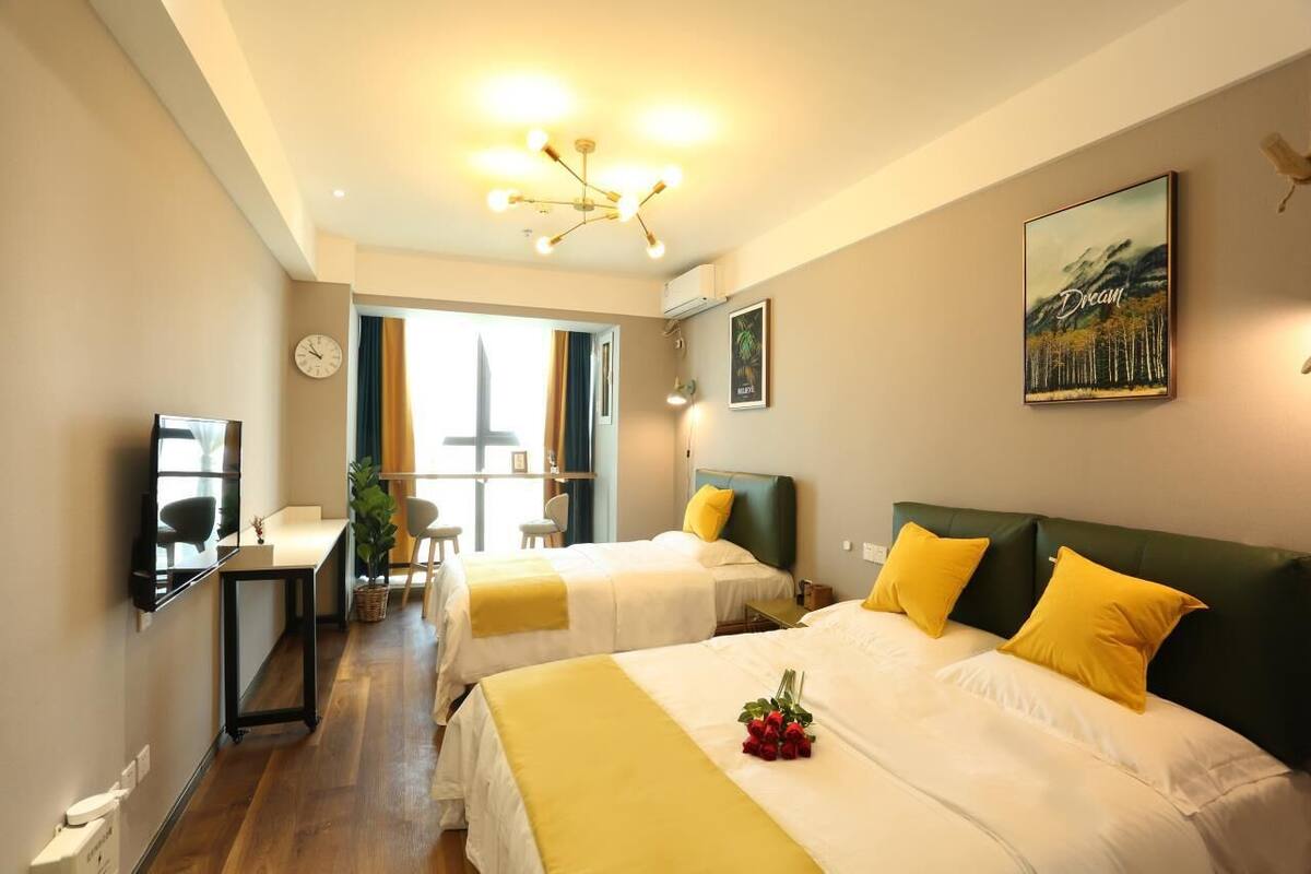 Une chambre d’hôtel avec deux lits, un bureau, une chaise, une horloge et un tableau au mur.