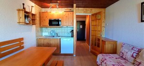 Cocina compacta con armarios de madera, microondas y lavavajillas.
