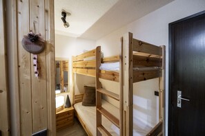 Habitación con literas de madera, una mesita de noche y un cartel de bienvenida.