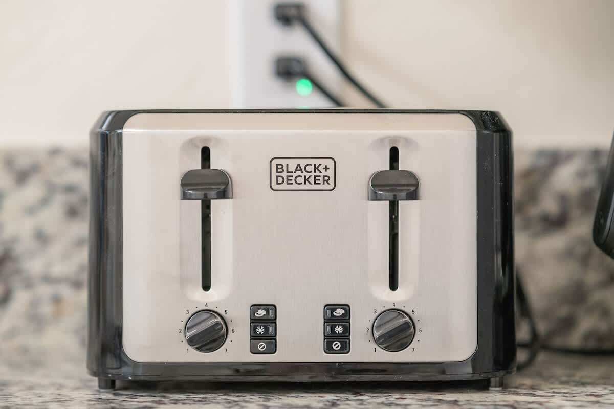 Un tostador BLACK+DECKER con dos ranuras, dos perillas de control y un cable de alimentación conectado.