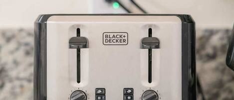Un tostador BLACK+DECKER con dos ranuras, dos perillas de control y un cable de alimentación conectado.