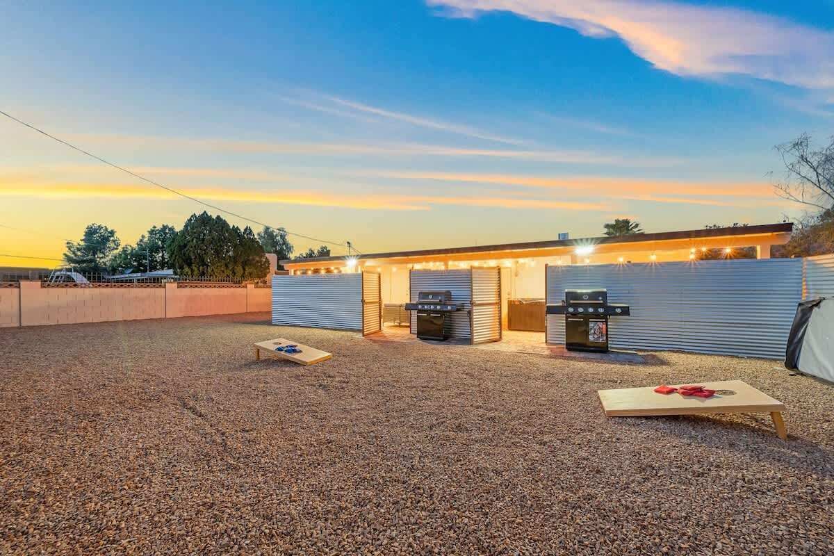 Un patio al aire libre con una parrilla, un área de estar techada y suelo de grava.