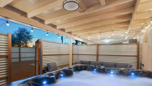 A hot tub area with a wooden ceiling and metal walls, surrounded by seating and string lights. - 3BR 2BA Home w Jacuzzi Near Reid Park & Zoo Unit A (Tucson)