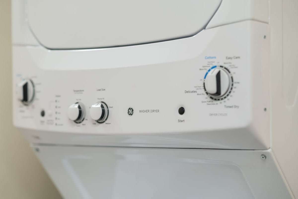 A front view of a GE washer and dryer unit with control knobs and labels for various functions.