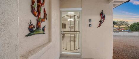 A building entrance with a glass door, decorative wall art, and a clear view of the surrounding area.