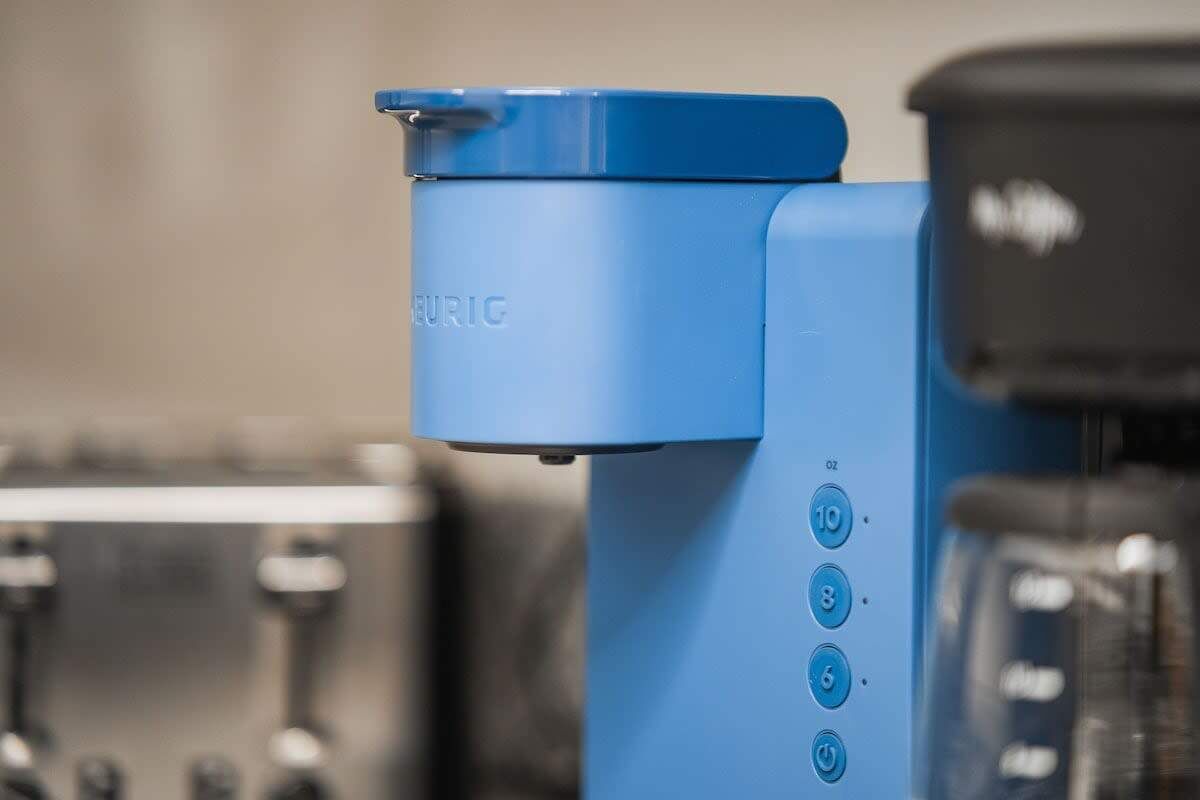 A blue coffee machine with a digital display and buttons for settings.