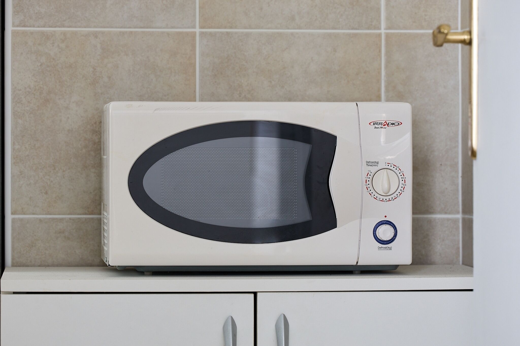 A white microwave oven with a digital display and control buttons on a kitchen counter.