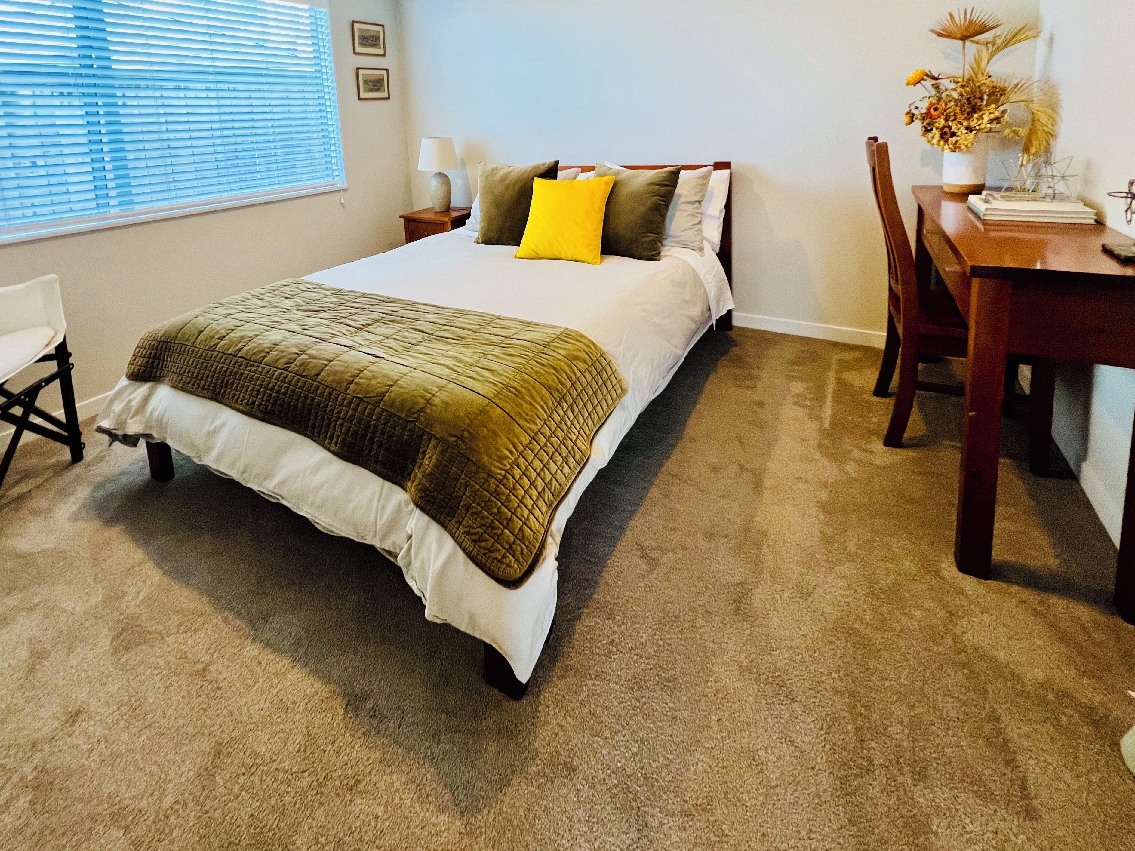 A neatly arranged bedroom with a bed, a desk, and a chair.