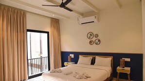 A hotel room with a bed, a ceiling fan, an air conditioning unit, a window with curtains, and a balcony. - Executive room in Arambol near Beach (Arambol)