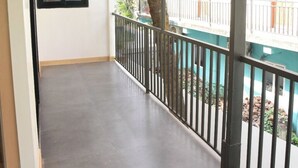 A balcony with a metal railing, a tiled floor, and a view of a residential building with balconies. - Executive room in Arambol near Beach (Arambol)