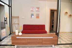 A modern living room with a red sofa, a wooden console table, and a vase with yellow flowers. - Executive room in Arambol near Beach (Arambol)
