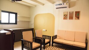 A compact living space with a kitchenette, a sofa, two chairs, a ceiling fan, and a patterned floor. - Executive room in Arambol near Beach (Arambol)