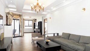 Ein geräumiges Wohnzimmer mit einem grauen Sofa, einem schwarzen Couchtisch und einer Chandelier.