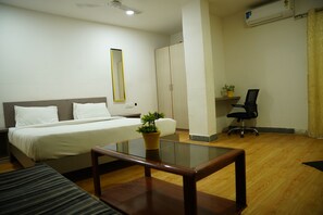 A hotel room with a bed, a small table, a chair, a desk, and a wardrobe. - Hotel Luxury Stay Inn (Hyderabad)