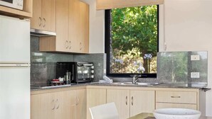 A modern kitchen with a built-in stove, microwave, and coffee maker. - Petra Olive 1 (Yallingup)