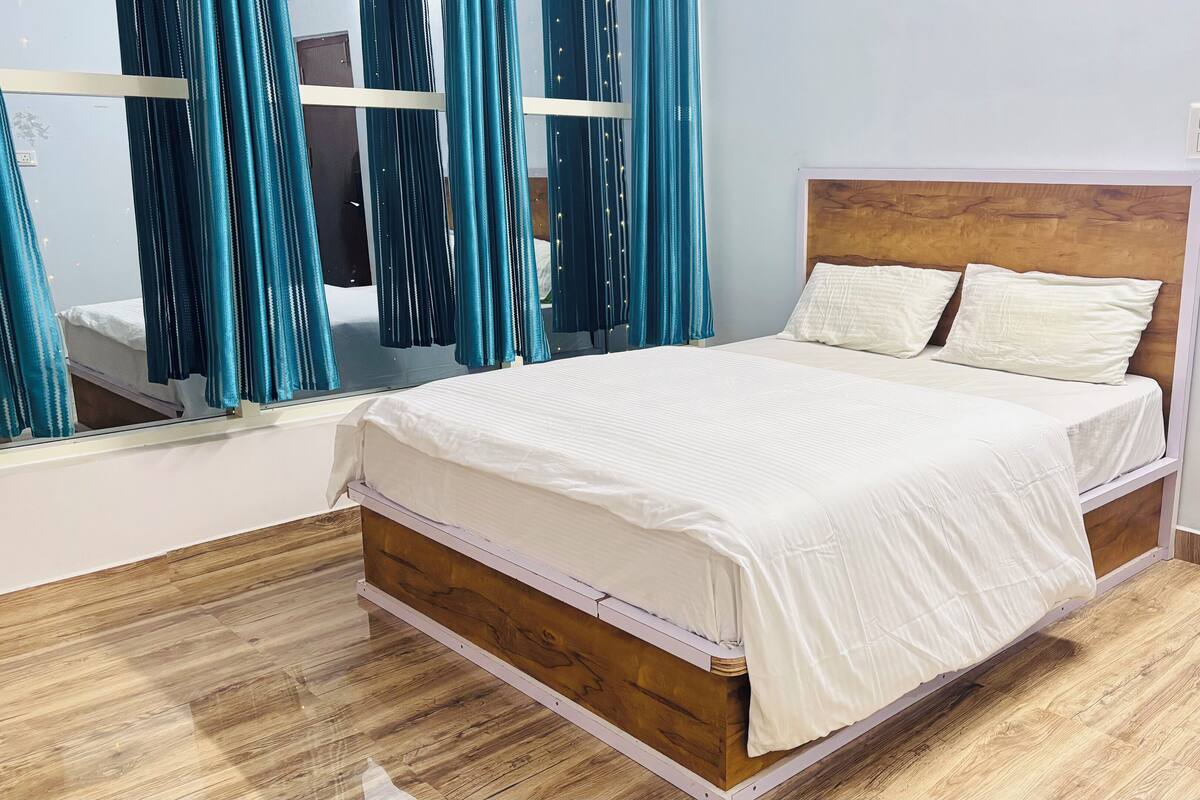 A neatly made bed with white bedding, a wooden headboard, and a mirror above it.