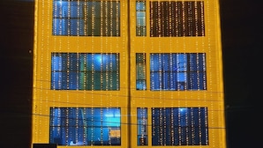 A multi-story building with a yellow facade and string lights. - I-ROOMZ S S V Hotel (Hoskote)