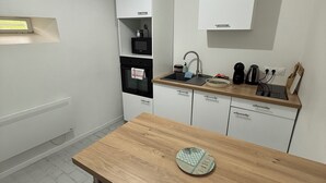 Una cucina moderna con mobili bianchi, un tavolo da pranzo in legno e un forno integrato.
