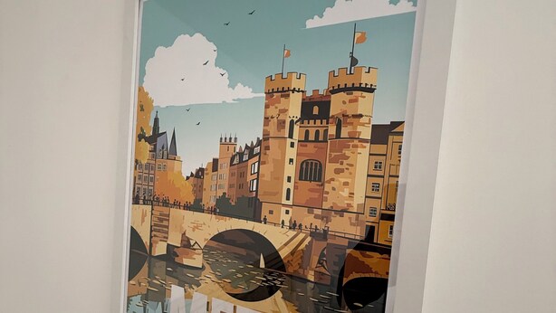 Un poster incorniciato che raffigura una veduta cittadina con un ponte, con la scritta 'METZ' nella parte inferiore.