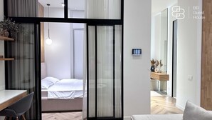 A modern guest room with a bed, a desk, and a chair. There is a TV mounted on the wall and a window with curtains. - Boulevard 46 (Tashkent)
