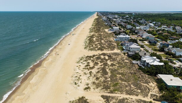 An aerial view of a coastal residential area with houses, a beach, and a water body. - Rusty Dolphin is a well-maintained 2 level home with pool and hot tub. (Virginia Beach)