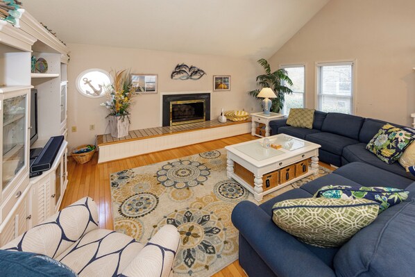 A living room with a fireplace, a sofa, a coffee table, and a television. - Rusty Dolphin is a well-maintained 2 level home with pool and hot tub. (Virginia Beach)