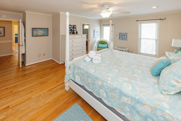 A bedroom with a four-poster bed, wooden flooring, and a ceiling fan. - Rusty Dolphin is a well-maintained 2 level home with pool and hot tub. (Virginia Beach)