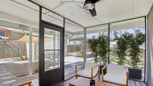 A covered patio with wooden furniture and a view of the backyard.