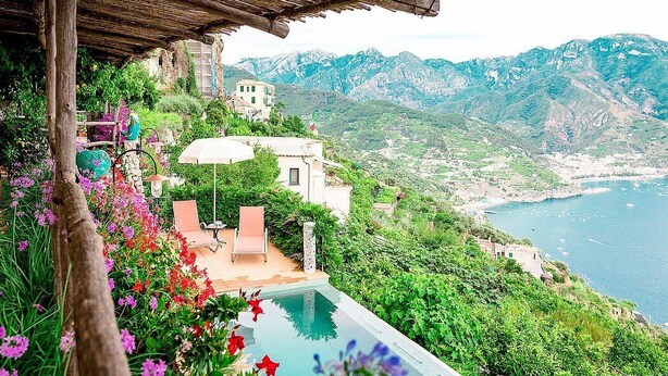 A private outdoor pool with a wooden pergola and a view of the sea and mountains.