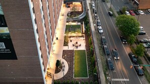 An aerial view of a hotel with a landscaped courtyard, parking area, and a building facade with a QR code.