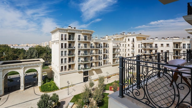 A multi-story residential building with balconies, a central courtyard, and a clear blue sky. - Boulevard 115 (Tashkent)