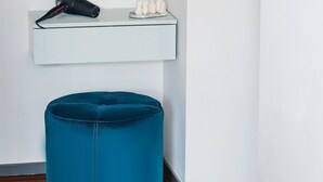A bathroom with a round mirror, a hairdryer, and a blue ottoman. - Boulevard 115 (Tashkent)