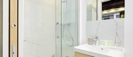 A modern bathroom with a glass-enclosed shower, a white marble sink, and a wooden vanity.