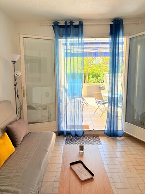 A room with a sofa, a coffee table, and a view of an outdoor patio area.